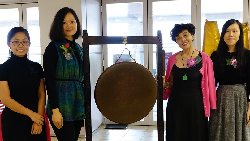 Four alumnae standing beside the famous "Gong" of Lady Ho Tung Hall